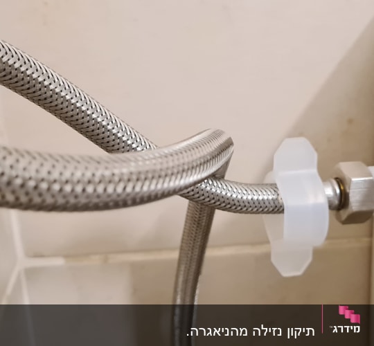 צינור מתכת מחובר לאסלה עם חיבור פלסטיק